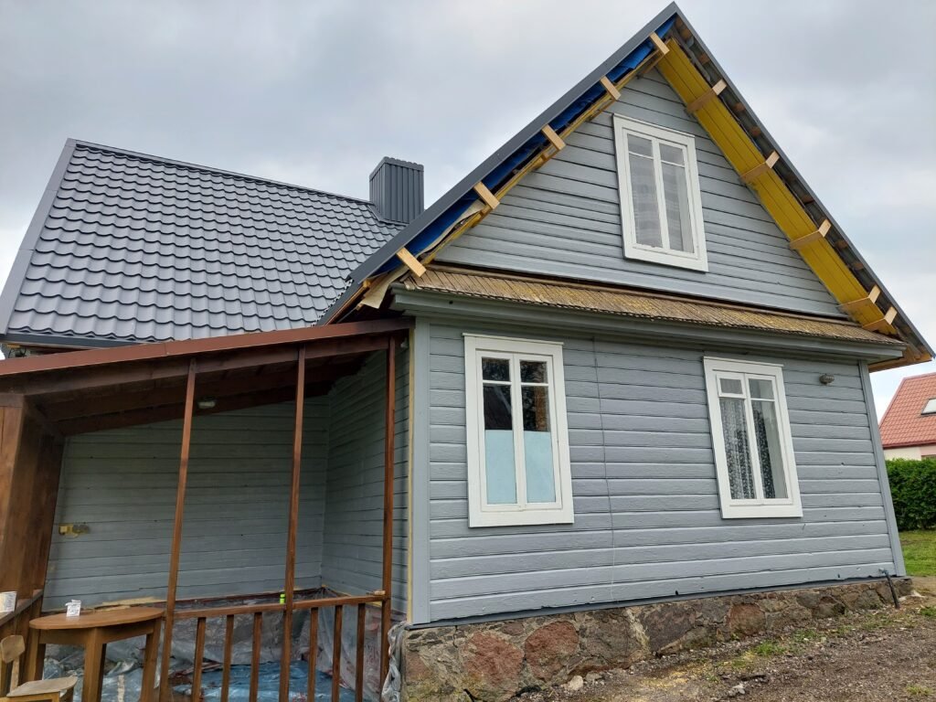 Ryškiai nudažytas medinis namas su lygiai padengtu paviršiumi