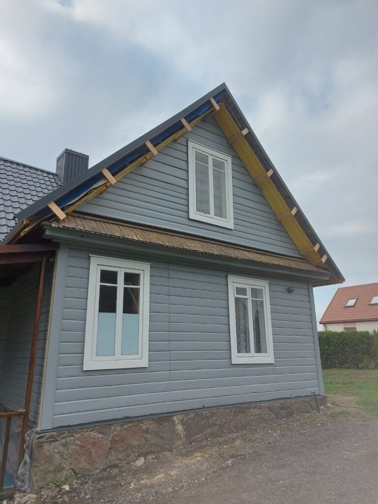 Atnaujintas medinio namo fasadas Utenos rajone – vientisas vaizdas po dažymo